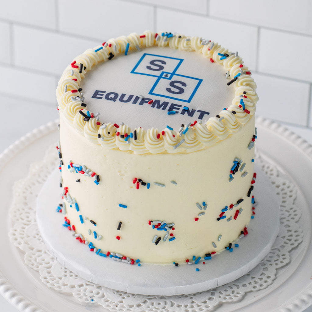 6-inch round cake with white frosting, red, white, and blue sprinkles, and a custom logo on top.