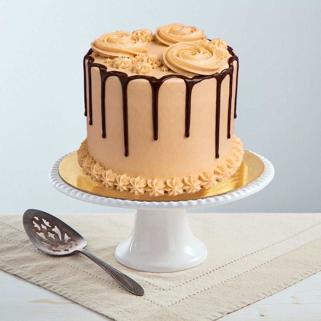 6-inch toffee cake with coffee frosting, dark chocolate drip, and piped rosettes on a white pedestal stand.